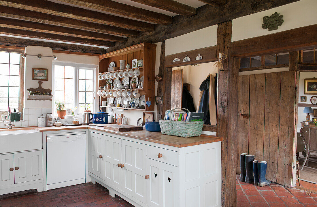 Weiße Einbauküche mit Geschirrkommode und Bücherkorb in High Halden cottage Kent England UK