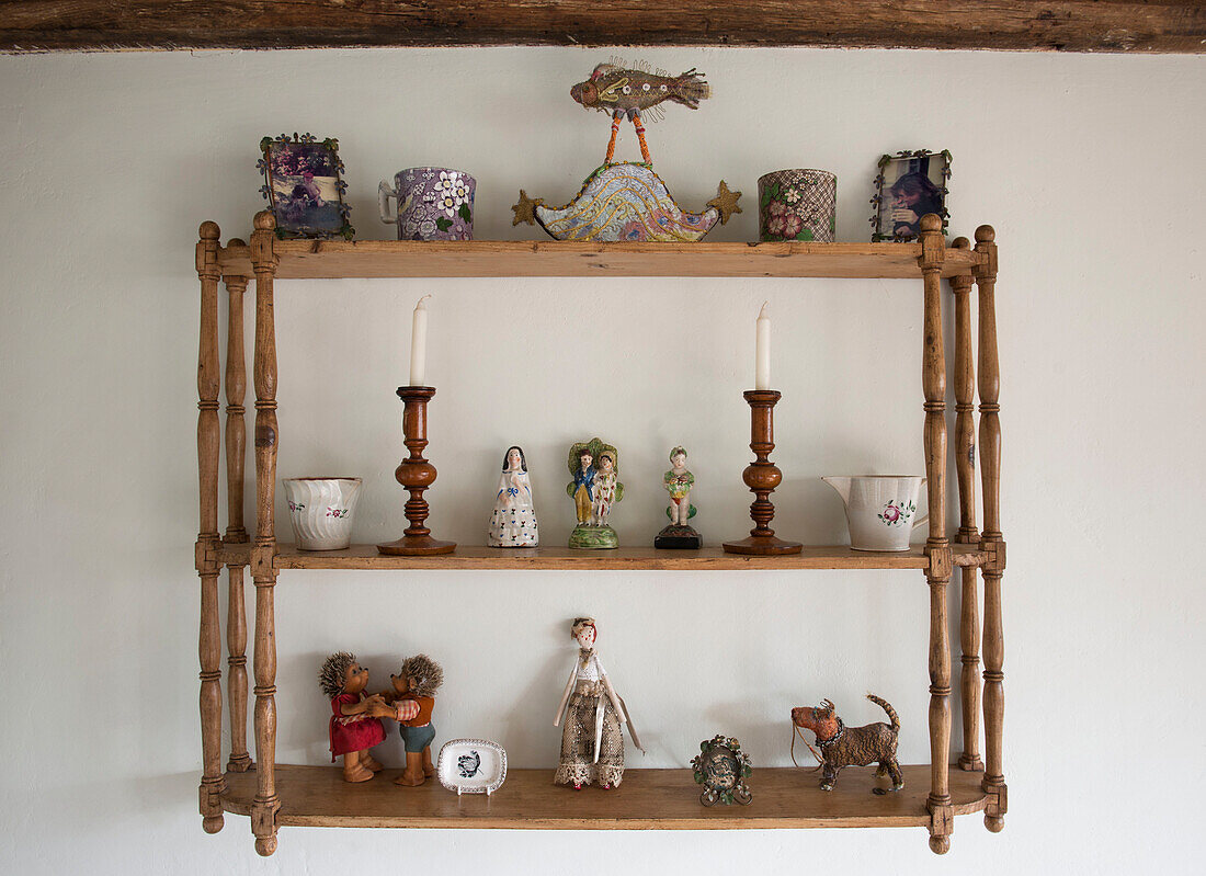 Sammlung von Ornamenten und Figuren auf einem an der Wand befestigten Holzregal in High Halden cottage Kent England UK