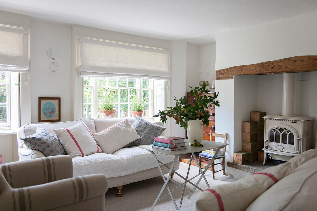Weißes Sofa am Fenster eines Wohnzimmers in Kent mit geschnittenen Apfelzweigen England UK