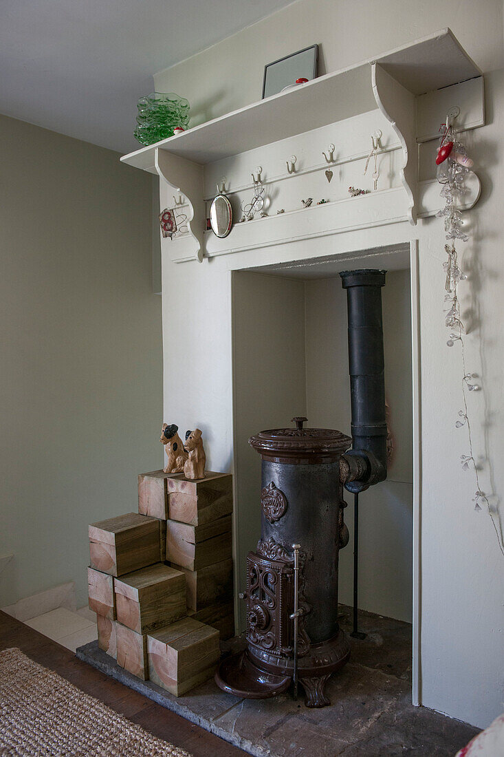 Vintage-Ofen und Brennholz mit Regal auf dem Kaminsims in einem Haus in Kent, England, UK