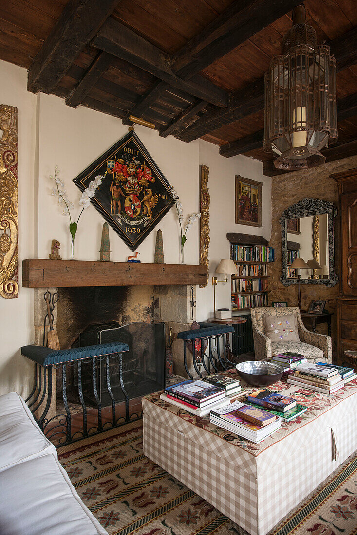 Bücher auf Ottomane am Kamin in einem Landhaus in der Dordogne in Frankreich