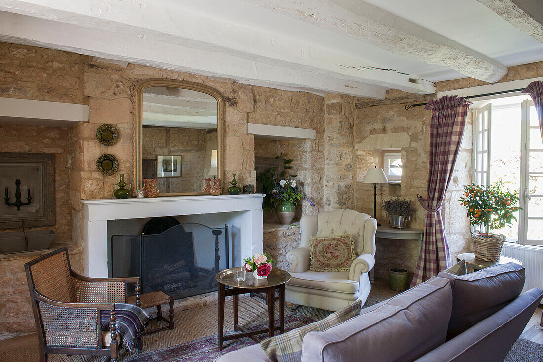 Armchairs at fireside with mirror in exposed stone Dordogne living room  Perigueux  France