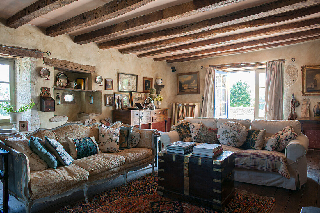Cushions on sofas with brass-edges travelling chest in beamed barn conversion in Lotte et Garonne  France