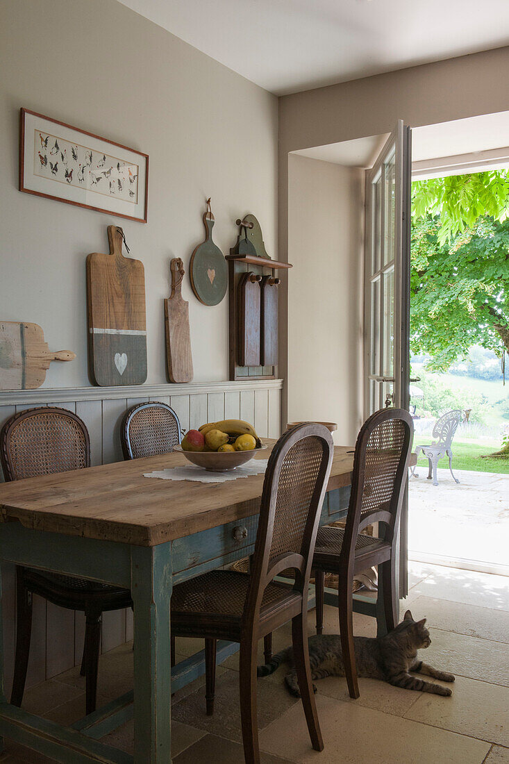 Wicker chairs at kitchen table with open back door in Dordogne  Perigueux  France