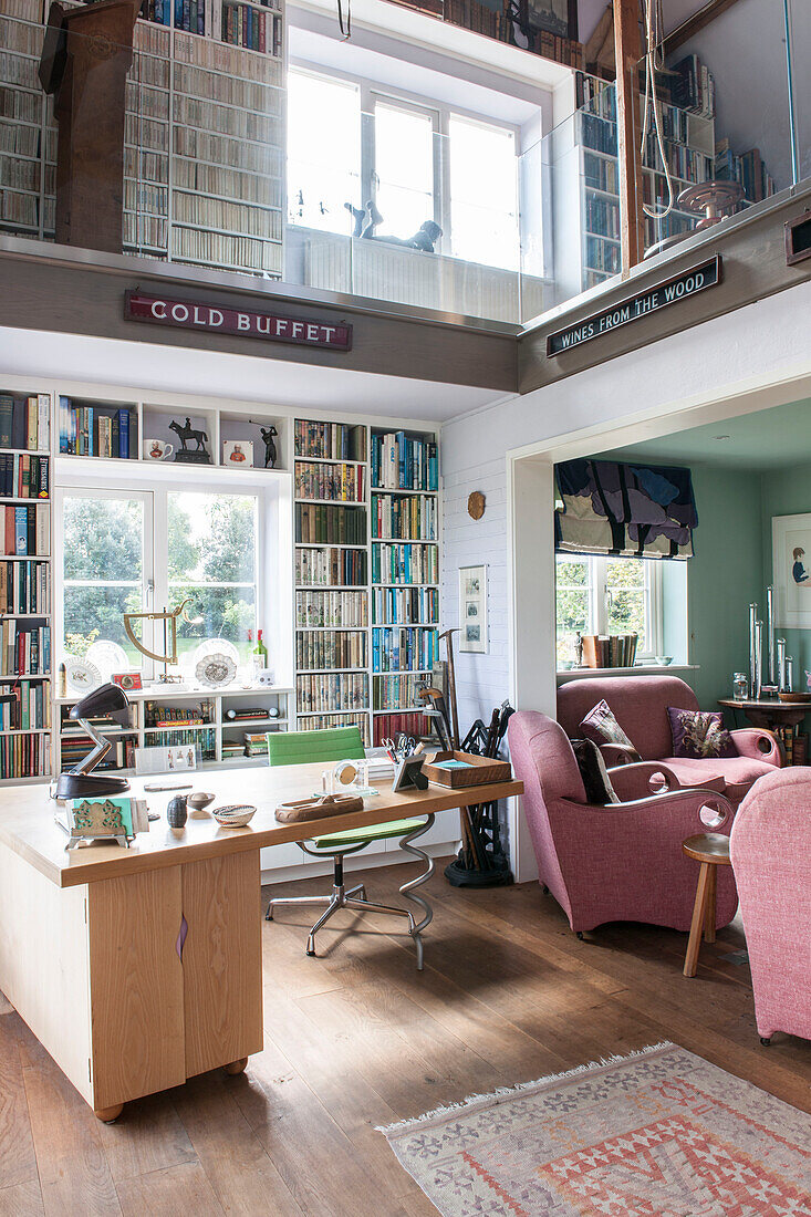 Bücherregale im Wohnzimmer mit doppelter Höhe in einem renovierten Landhaus in Norfolk, England UK