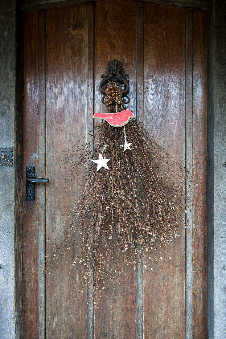 Trockenblumen und Weihnachtssterne an der hölzernen Eingangstür eines Hauses in Kilndown, Kent, England UK