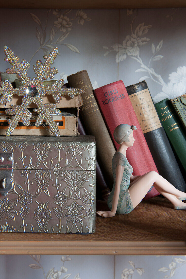 Figur im Stil der 1940er Jahre mit gebundenen Büchern und Schatulle mit Schneeflocke in Kilndown cottage Kent England UK