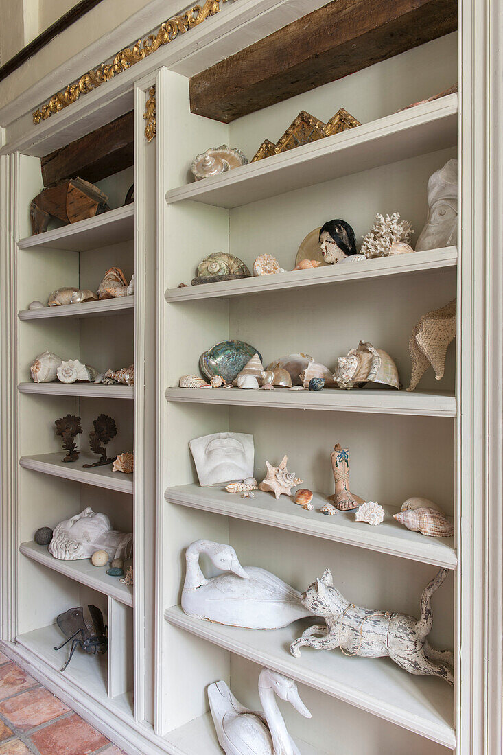 Muscheln und Ornamente in einem Regal in einem Hausflur in Suffolk, England, Vereinigtes Königreich