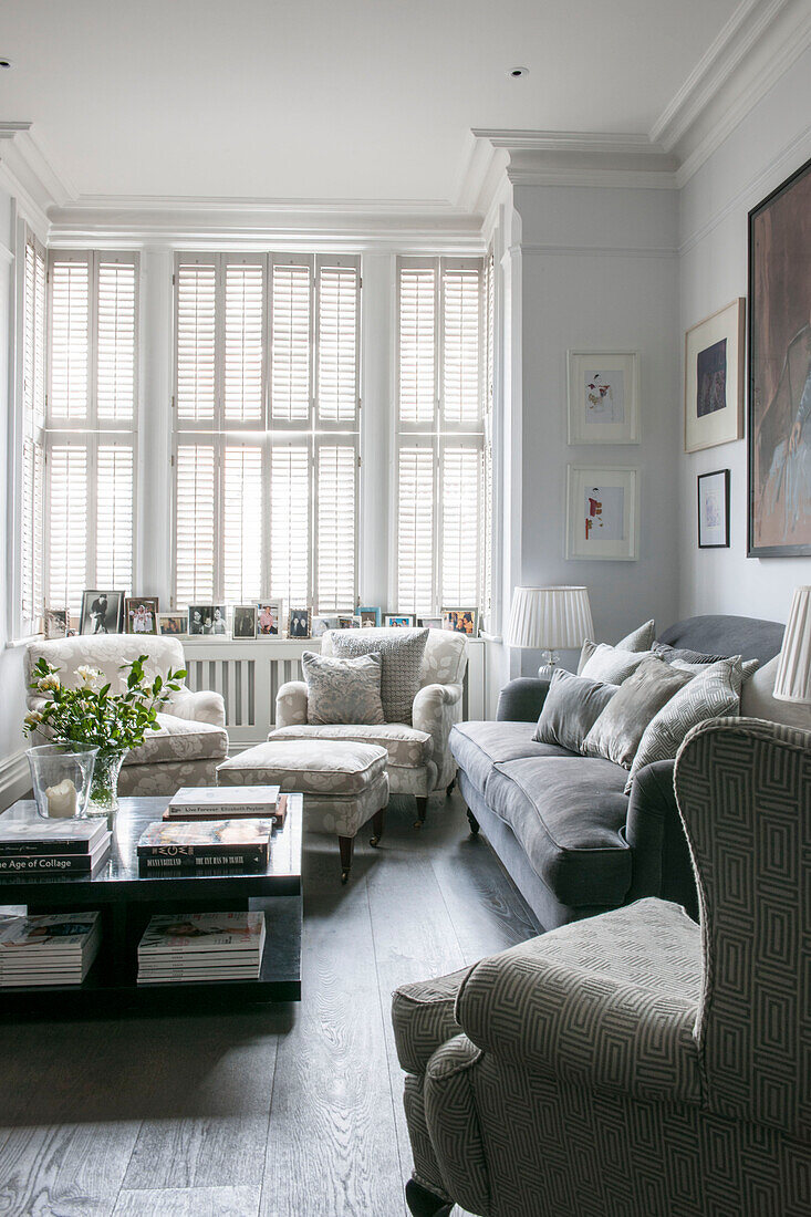 Closed shutters with armchairs and coffee table in living room of South London Victorian terraced house