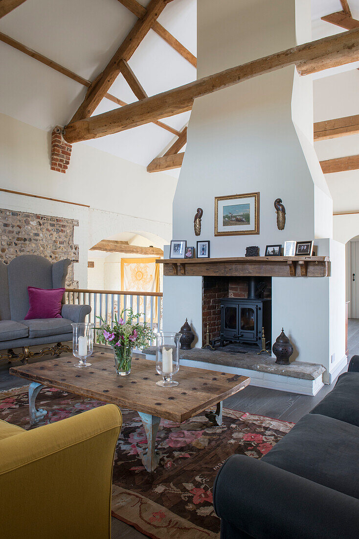 Yellow and grey sofas with chimney in beamed 18th century Norfolk barn conversion  England  UK