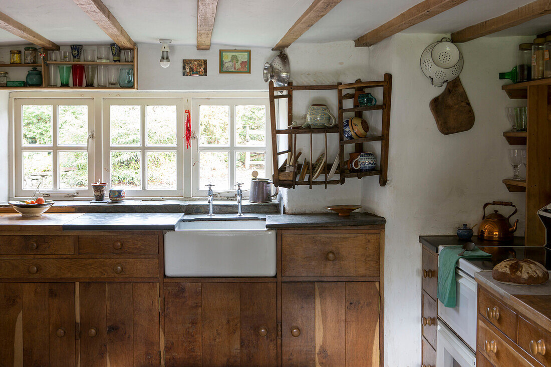 Belfast-Spülbecken mit Geschirr auf einem Holzregal am Fenster in einer Küche in Devon England UK