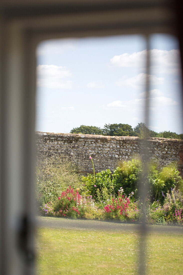 Blick durch ein Fenster auf den hinteren Garten eines Bauernhauses in Petworth, West Sussex, Kent