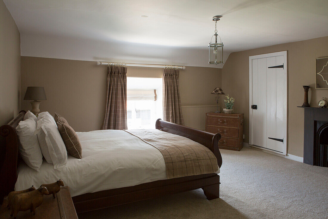 Co-ordinating brown fabrics in carpeted double bedroom of Petworth farmhouse West Sussex Kent