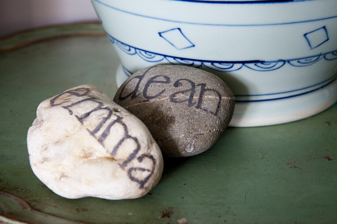 Kieselsteine mit Schriftzug und Schale in einem Haus in Amberley, West Sussex, England, UK