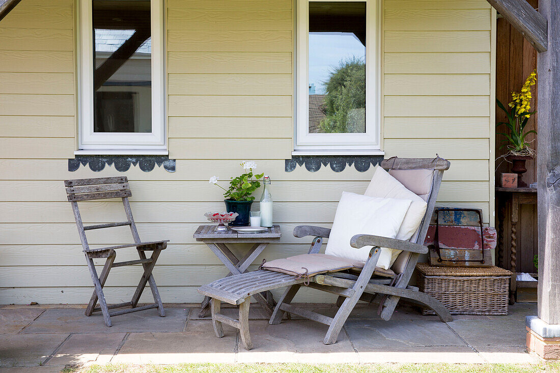 Alter Holzsessel und Stuhl auf der Terrasse eines Strandhauses in West Wittering, West Sussex, England