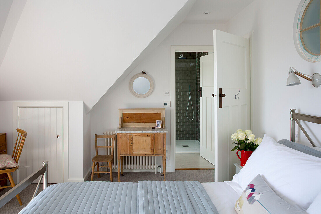 Holztisch und -stuhl mit eigenem Bad im Schlafzimmer im Dachgeschoss eines Hauses in West Wittering, West Sussex, England