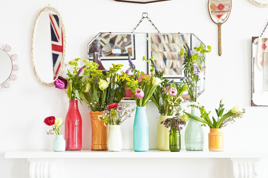 Schnittblumen in Vasen auf dem Kaminsims mit Spiegeln in einem Haus einer Londoner Familie, England, UK