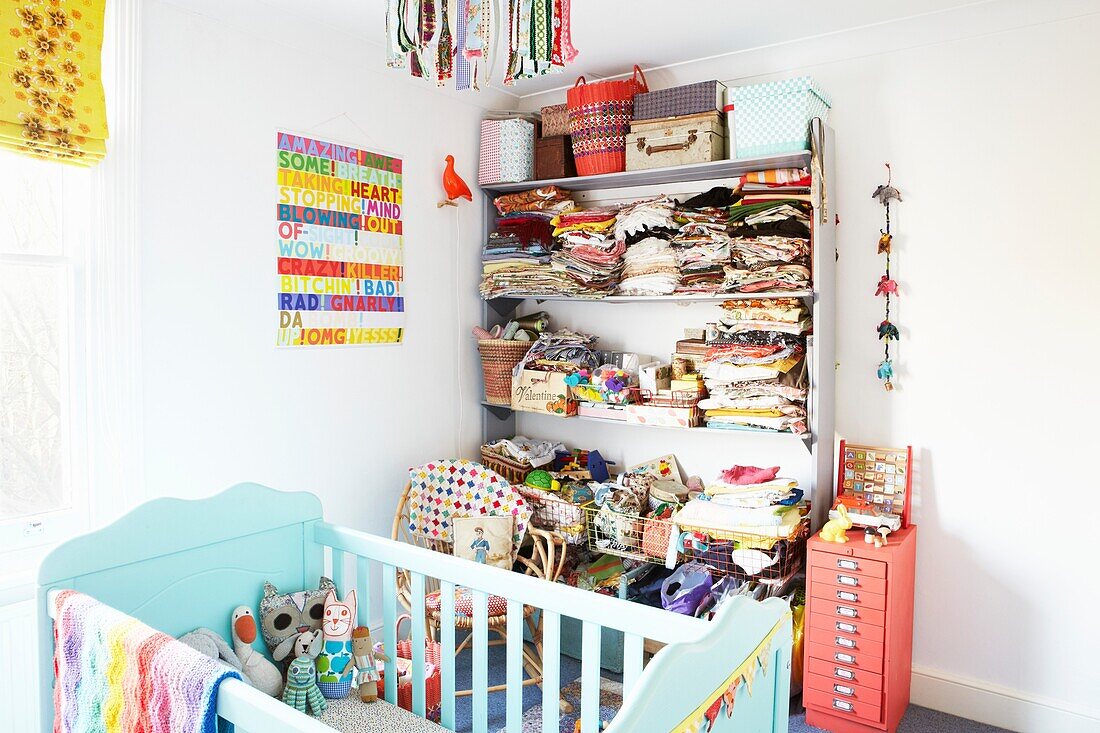 Gefaltete Kleidung auf einem Regal im Kinderzimmer mit türkis gestrichenem Kinderbett, Haus einer Londoner Familie, England, UK