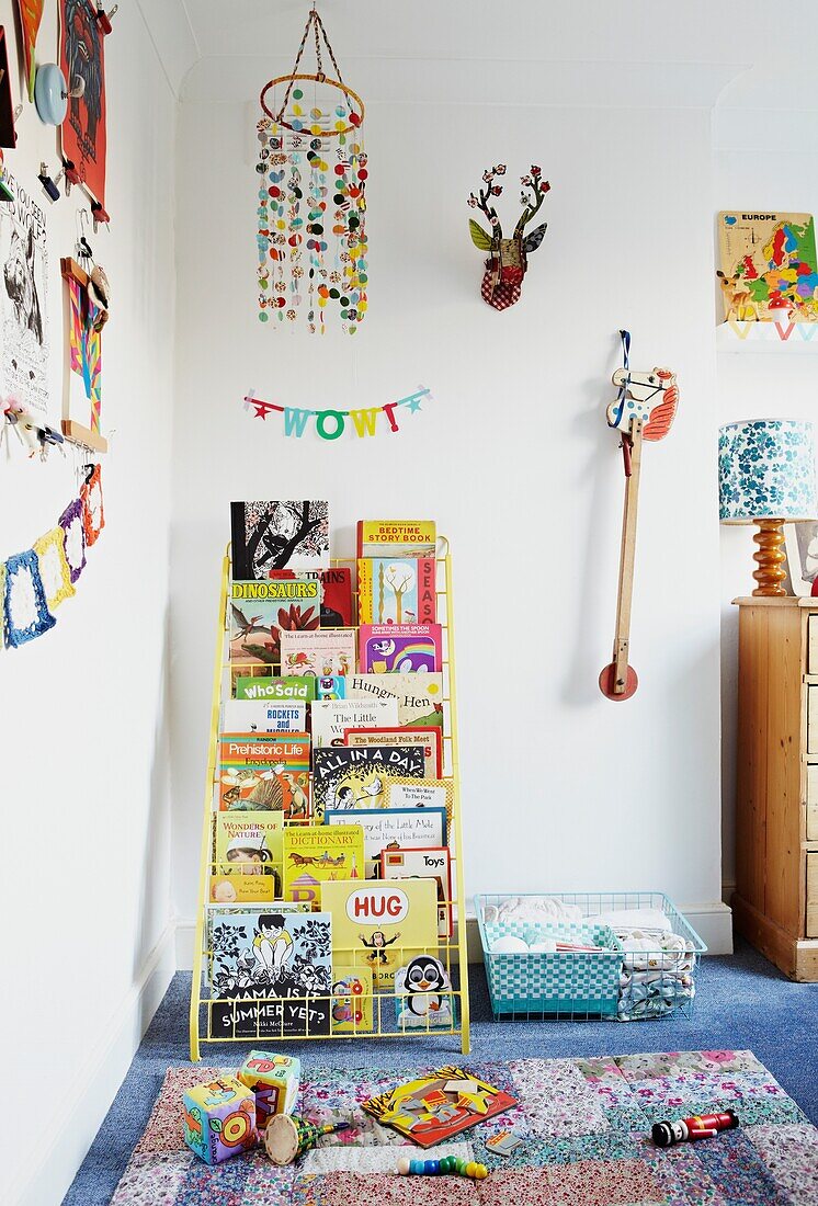 Bücherregal und Spielzeug im mit Teppich ausgelegten Kinderzimmer einer Londoner Familie, England, UK
