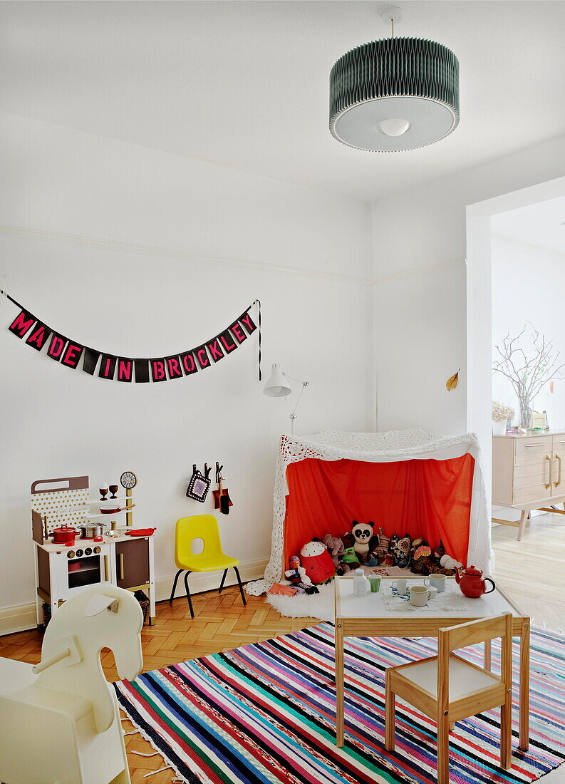 Playroom with table and chairs on striped rug in London family home  England  UK