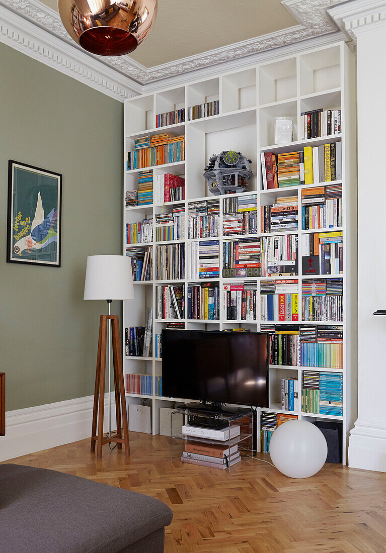 Full length bookcase with TV in parquet living room of London family home  England  UK