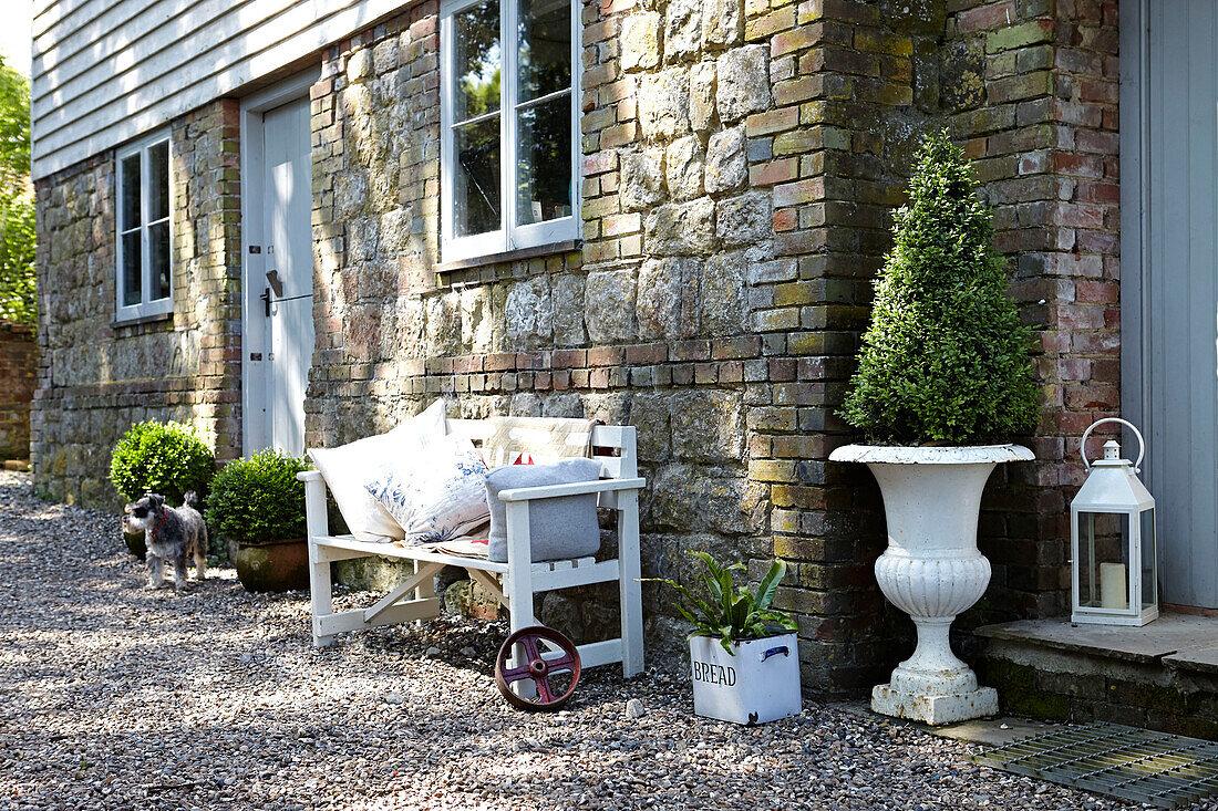 Sitzbank mit Steinmauerwerk und Wetterschutzplatten an der Außenseite eines Hauses im ländlichen Großbritannien
