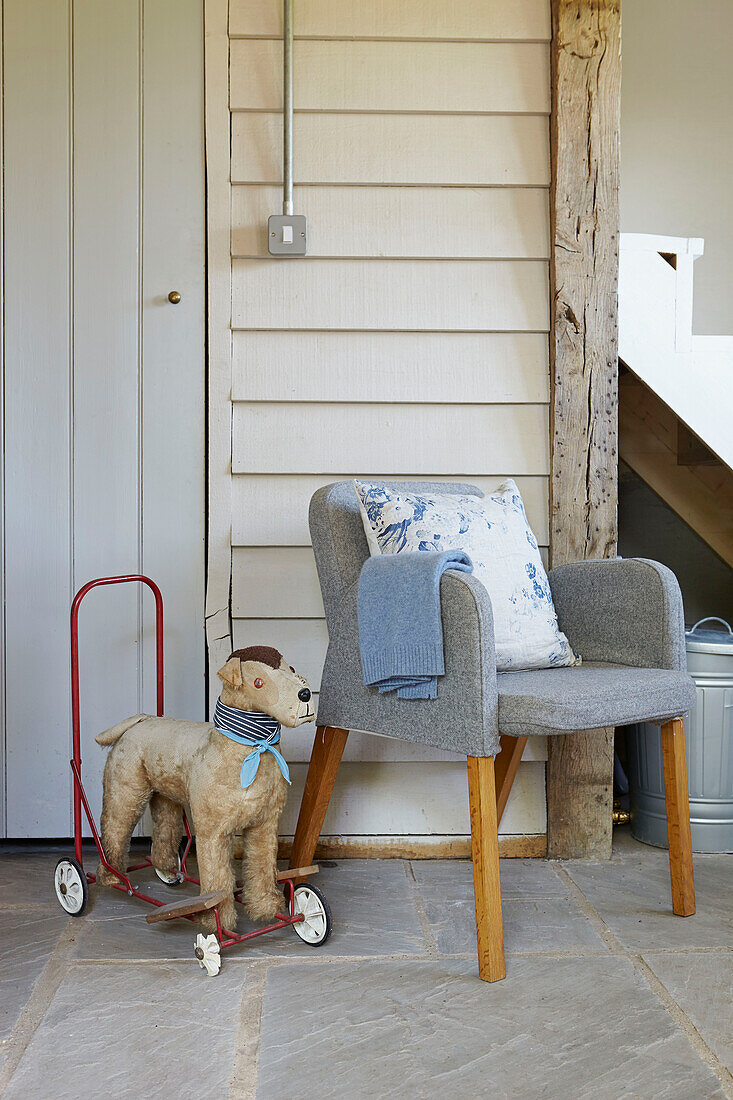 Hellgrauer Sessel mit altem Spielzeughund im Flur eines britischen Bauernhauses