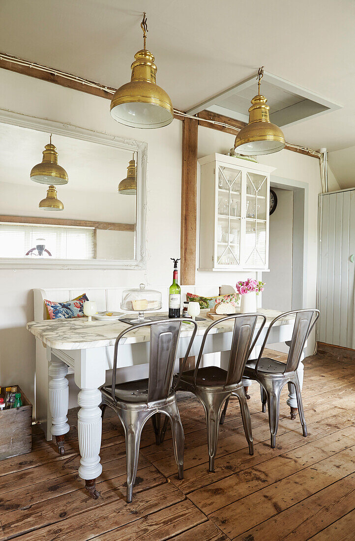 Copper pendant lights above table with mirror in UK farmhouse kitchen