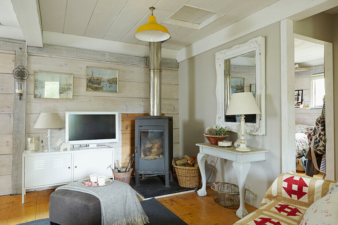 TV auf Sideboard mit Holzofen im Wohnzimmer eines britischen Bauernhauses
