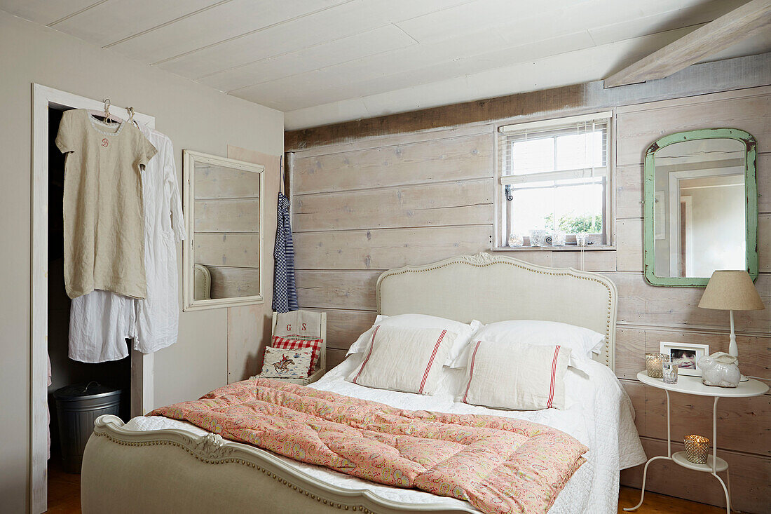 Steppdecke auf Doppelbett mit hellgrünem Spiegel an getäfelter Wand im Schlafzimmer eines britischen Bauernhauses