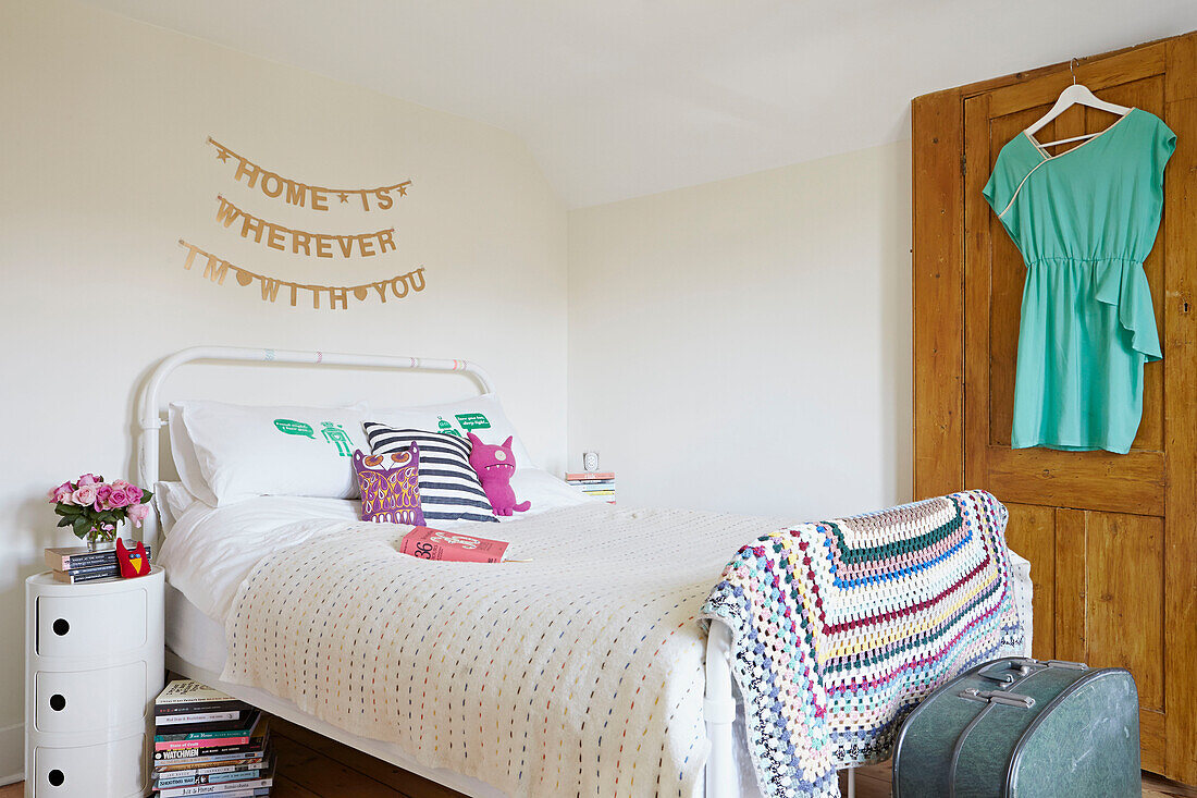 Einzelbett mit gehäkelter Decke und Bluse, die an der Rückseite der Tür in einem Londoner Schlafzimmer hängen, England, UK