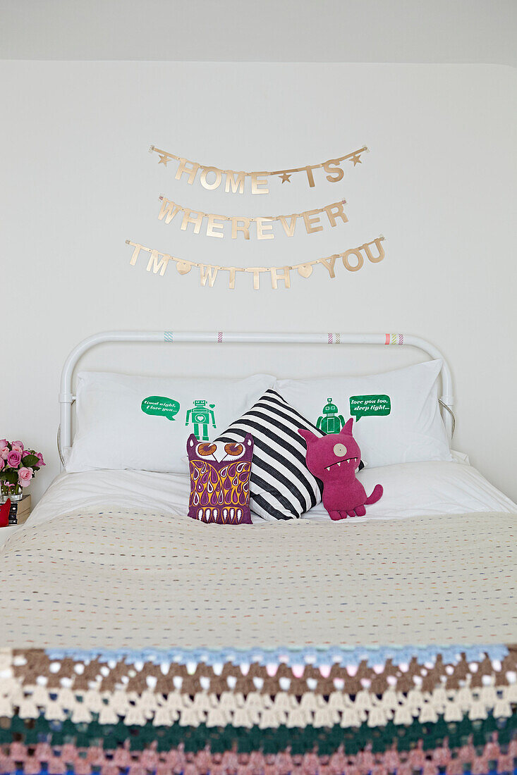 Novelty cushions on bed with crochet blanket in London home,  England,  UK