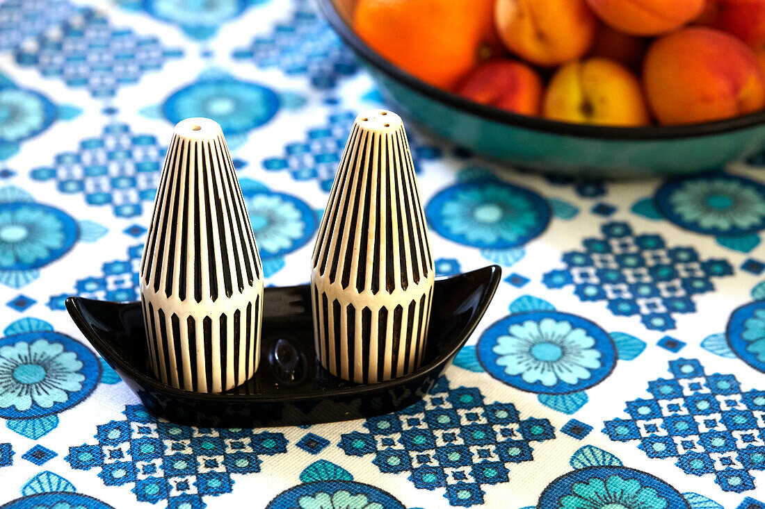 Salt and pepper pots on retro style tablecloth in Brabourne farmhouse kitchen,  Kent,  UK