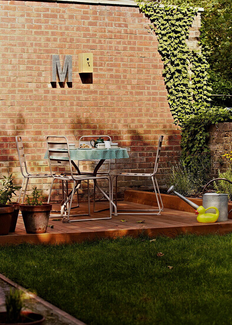 Überdachte Terrasse mit Tisch und Stühlen in einem ummauerten Garten vor einem Londoner Einfamilienhaus England UK