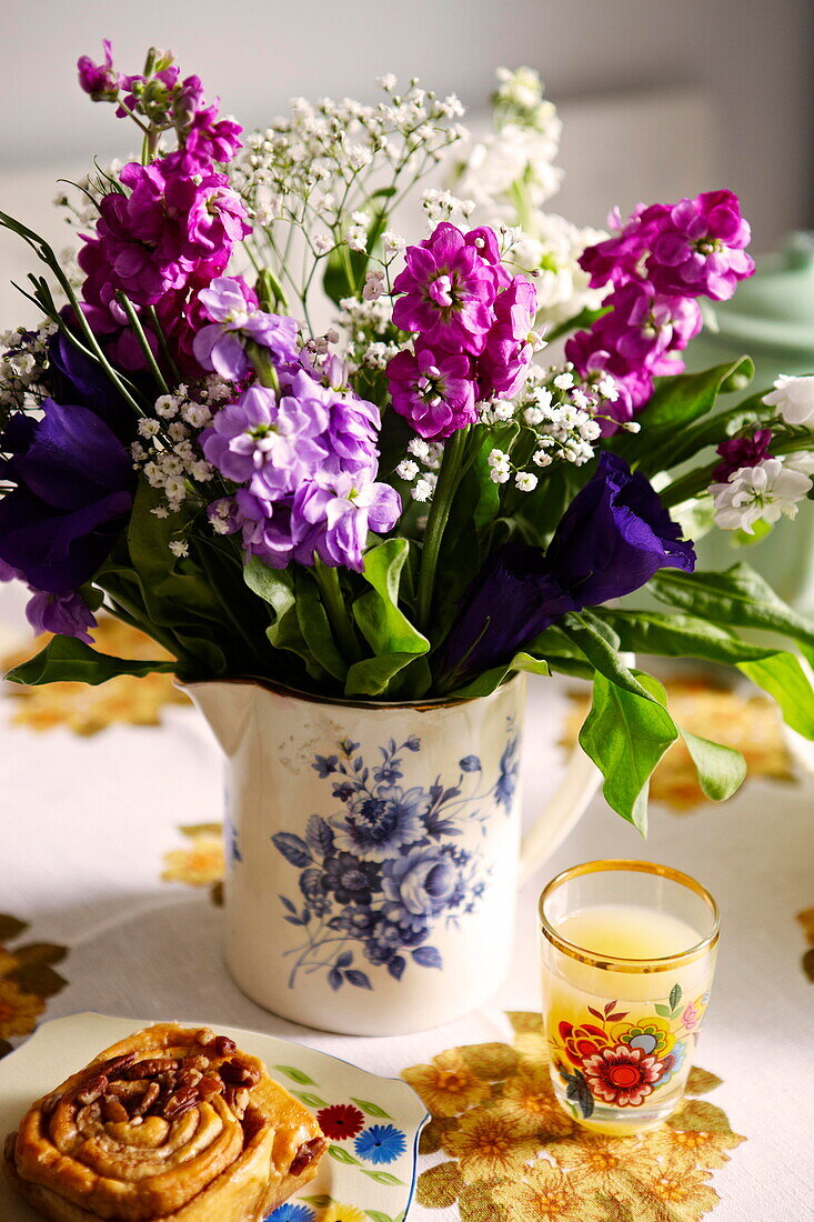 Schnittblumen mit dänischem Gebäck und Saft auf einem Tisch in einem Haus in Birmingham, England UK