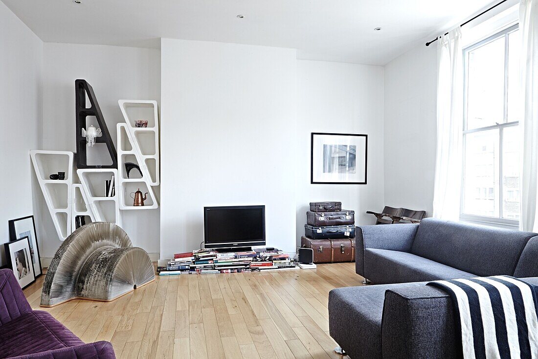 Regal und graues Sofa im Wohnzimmer eines modernen Londoner Einfamilienhauses England UK