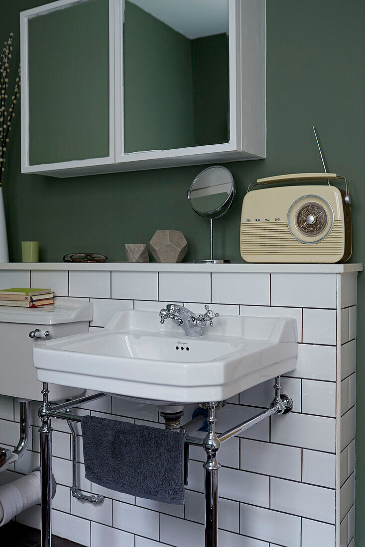 Wandverspiegelter Schrank mit Vintage-Radio im weiß gefliesten Badezimmer eines zeitgenössischen Londoner Hauses England UK