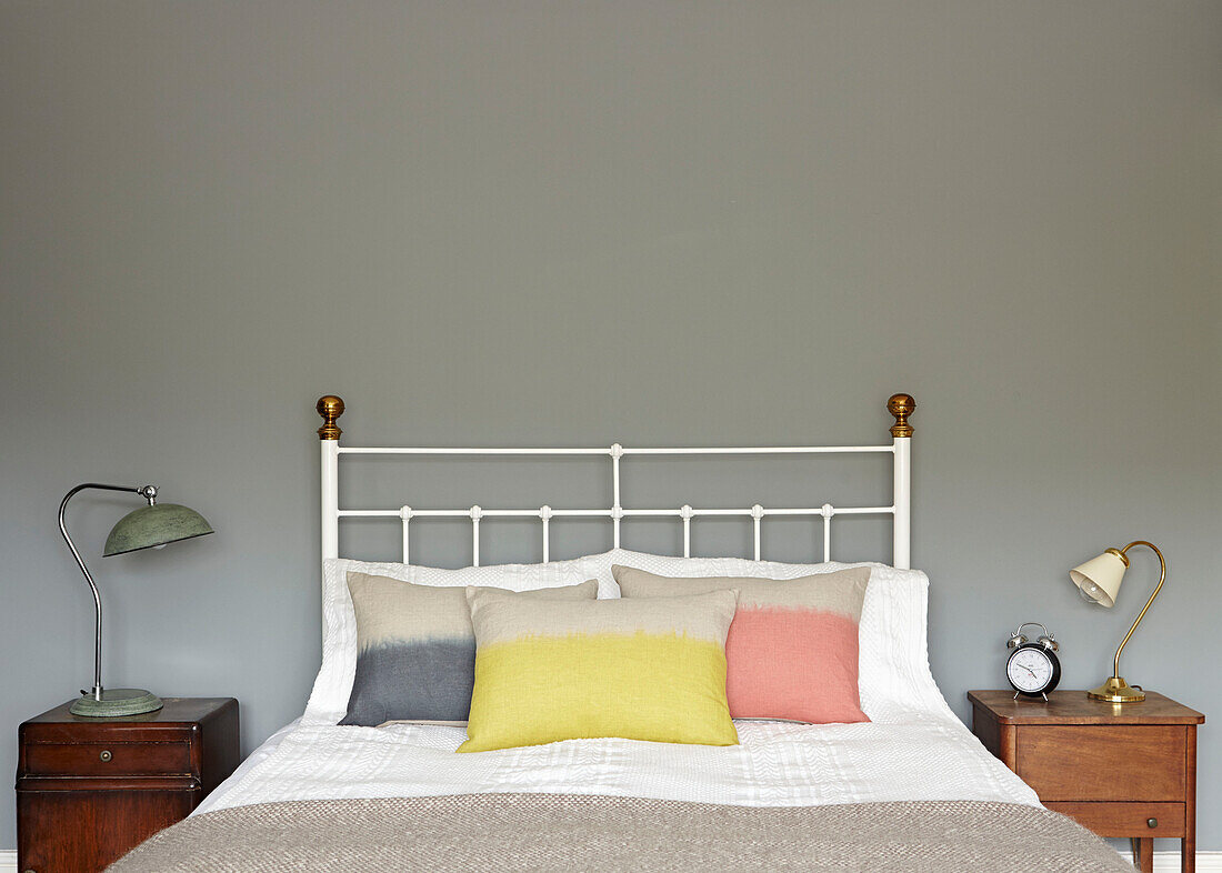 Pastellfarbene Kissen auf einem Doppelbett mit Nachttischen im Vintage-Stil in einer modernen Londoner Wohnung England UK