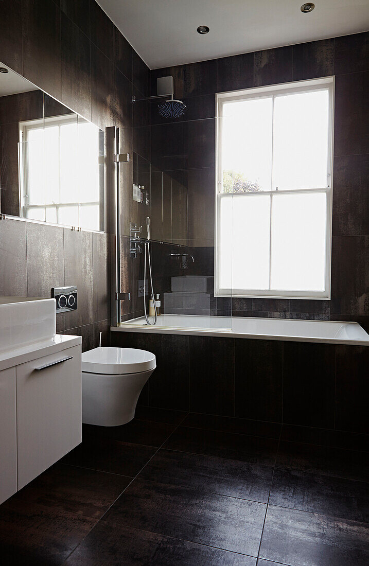 Unverkleidetes Fenster über dem Bad mit Spiegel, der das Licht reflektiert, in einem Londoner Stadthaus England UK