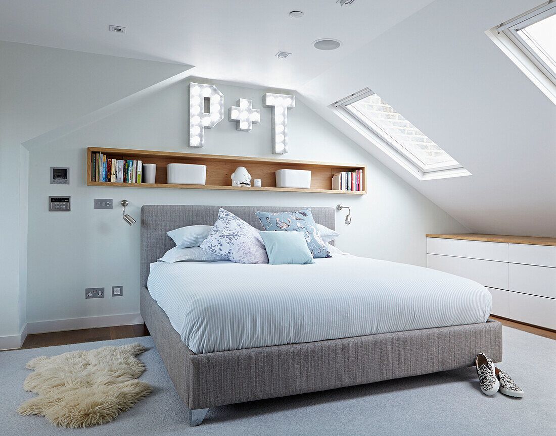 Oberlichtfenster über Doppelbett mit Holzregal und Buchstaben 'P' und 'T' in Londoner Stadthaus England UK