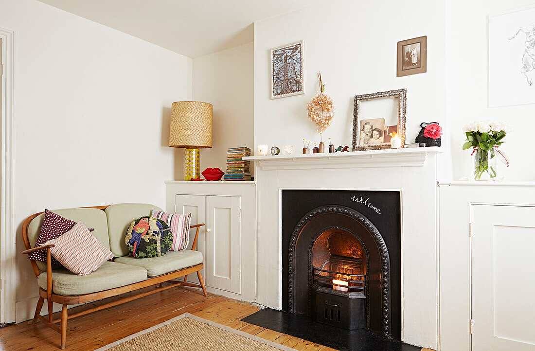 Victorian fireplace with wooden sofa in living room of Faversham home,  Kent,  UK
