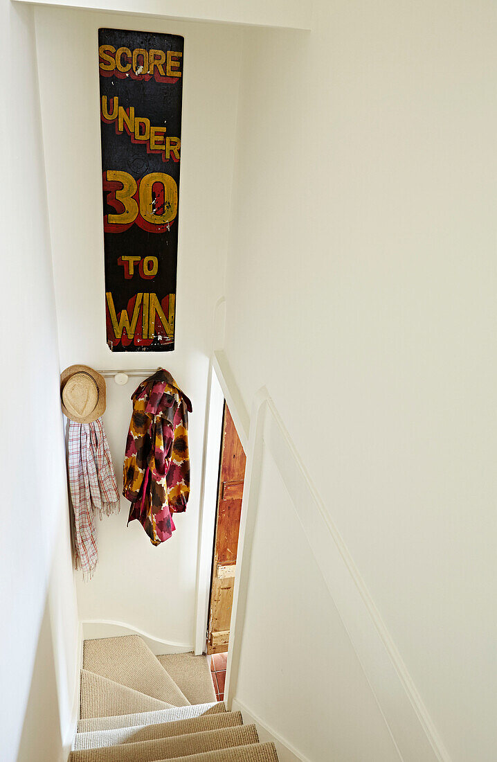 Handgemaltes Schild über den Kleiderhaken im engen Treppenhaus eines Hauses in Faversham, Kent, UK