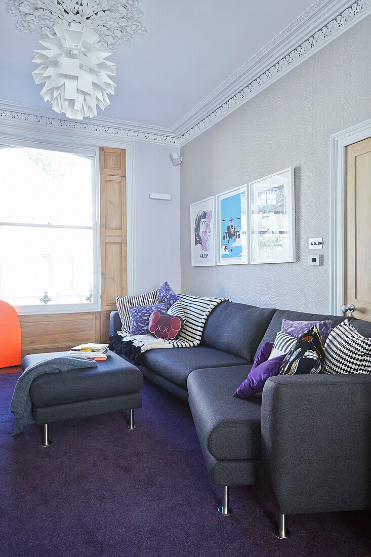 Graues Sofa im Wohnzimmer eines Londoner Stadthauses mit lila Teppichboden England UK