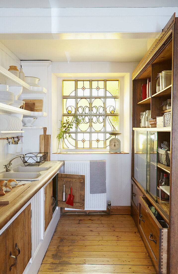 Hand mit Kehrschaufel und Besen an der Innenseite einer Schranktür in einer Küche in West Yorkshire mit Glasfenster UK