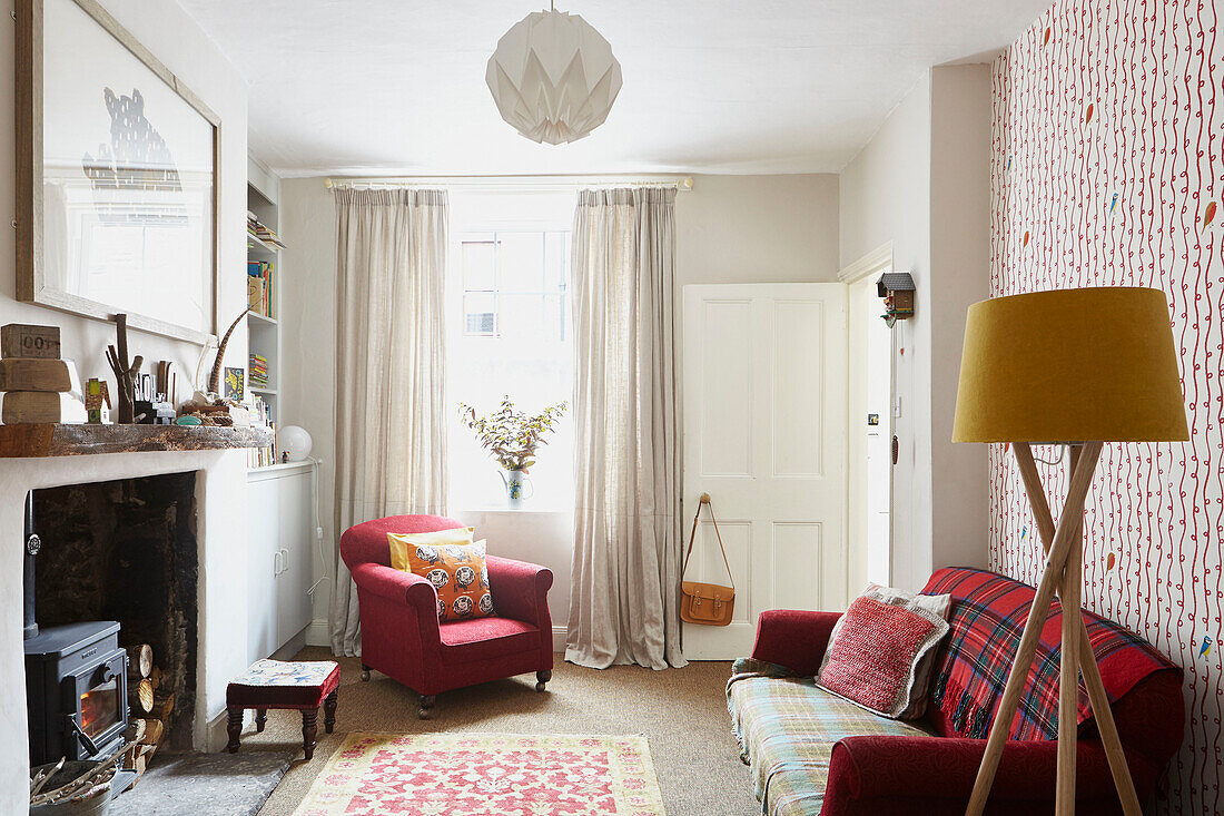 Roter Sessel am Wohnzimmerfenster mit Kaminofen und Sofa in Berwick Upon Tweed Northumberland UK