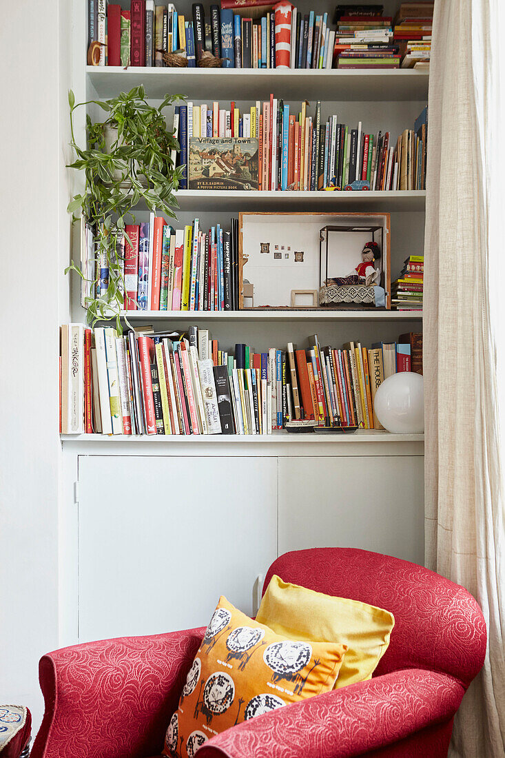Red armchair below bookcase in Berwick Upon Tweed living room  Northumberland  UK