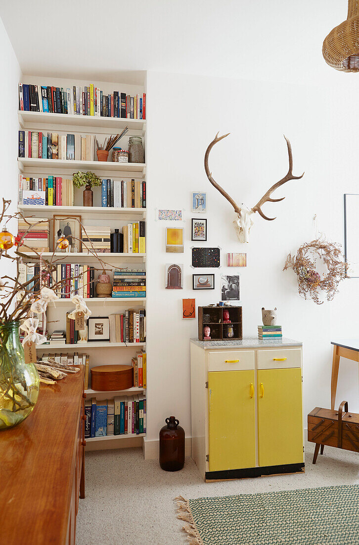 Geweih über gelbem Schrank mit Bücherregal in Londoner Wohnung UK