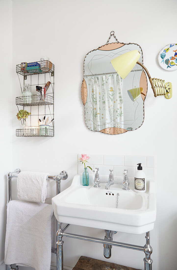 Vintage mirror above washbasin with bathroom wall rack in London home  UK