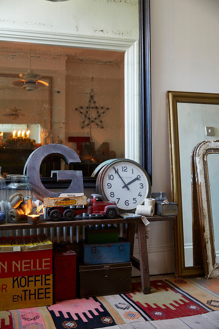 Buchstabe 'G' und Uhr mit einer Sammlung von Vintage-Ornamenten und einem großen Spiegel im Flur eines Hauses in Rochester, Kent, Großbritannien