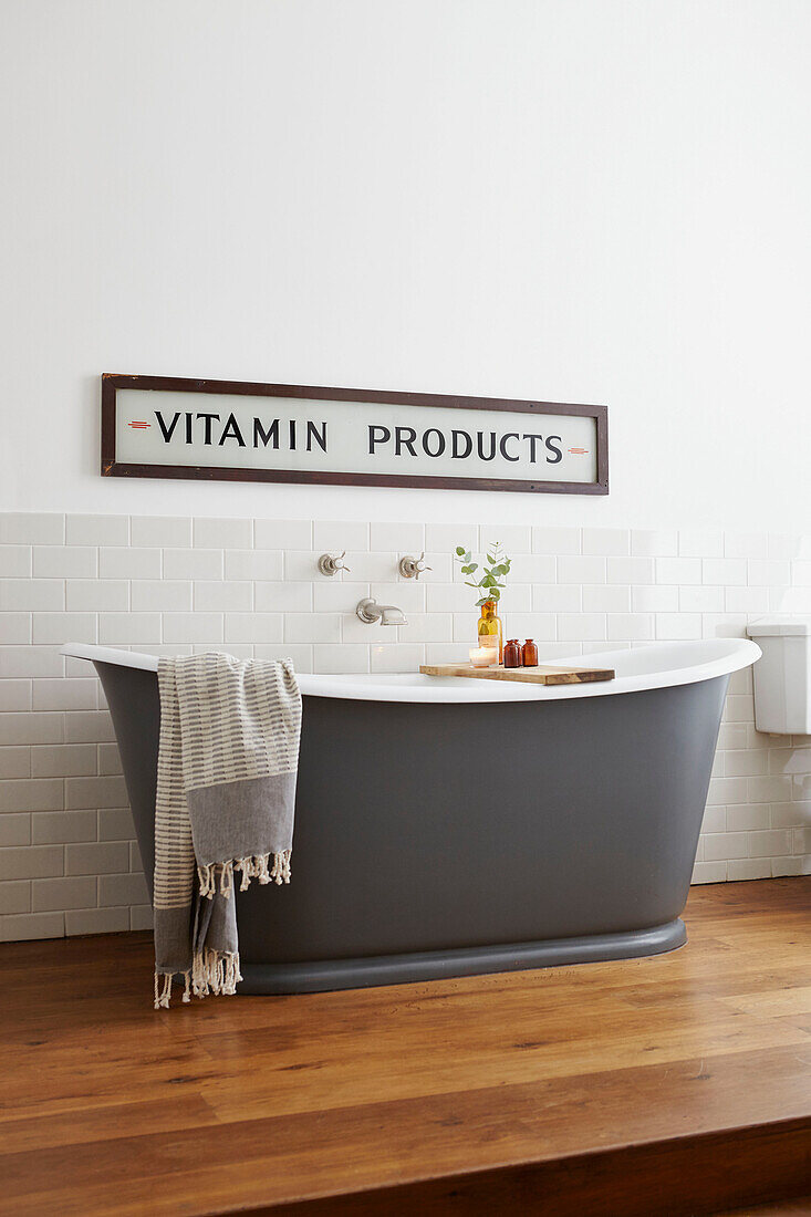 'Vitamin products' sign above modern grey freestanding bathtub in London home  UK